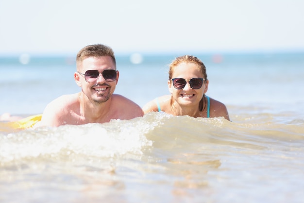 Jeune heureux beau couple femme et homme allongé dans l'eau de mer