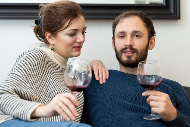 Jeune et heureux couple buvant du vin et se relaxant à la maison