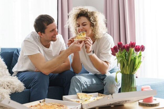 Jeune et heureux couple mangeant de délicieuses pizzas à la maison