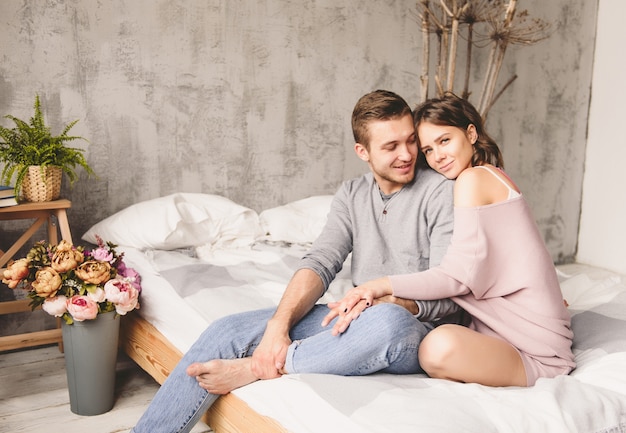 jeune hipster avec barbe et jolie femme au repos à la maison tout en restant assis sur le lit à la maison