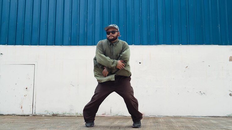 Photo jeune hipster dansant bboy pas de pied dans la rue avec mur bleu hiphop