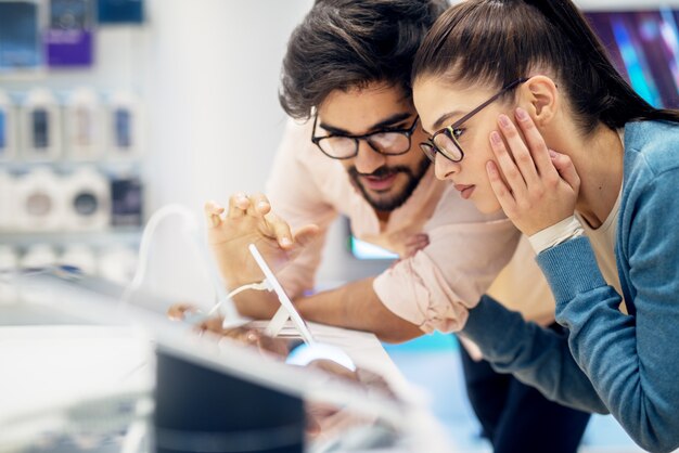 Jeune hipster élégant couple multiracial souriant testant le nouveau téléphone