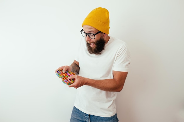 Un jeune hipster élégant et joyeux avec une barbe joue avec un jouet populaire pop it Jouet anti-stress sensoriel fidget push pop