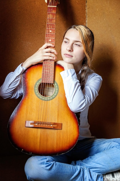 Jeune hipster femme assise sur le sol et jouant de la guitare à la maison Adolescente apprenant à jouer de la chanson et à écrire de la musique dans sa chambre Mode de vie passe-temps se détendre Concept d'éducation aux loisirs instrument