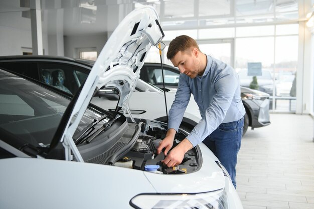 Un jeune homme achète sa première voiture électrique dans la salle d'exposition Eco concept de vente de voitures
