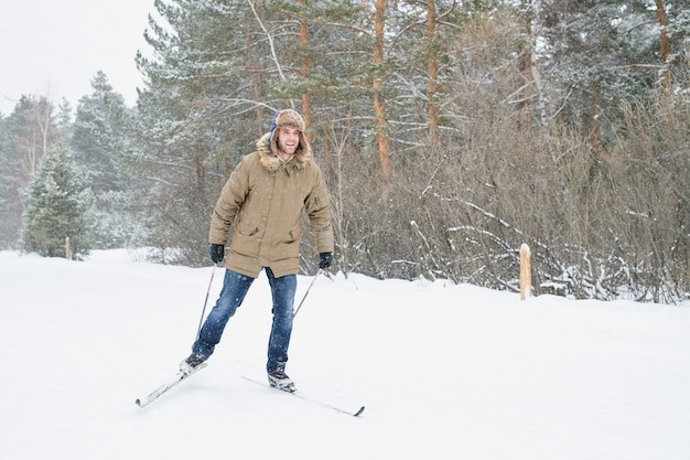 Jeune homme actif ski dans la forêt d'hiver