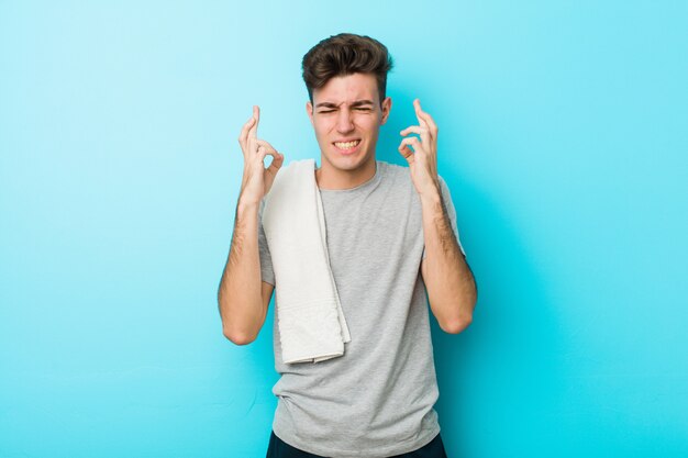 Jeune homme adolescent de remise en forme, croisant les doigts pour avoir de la chance