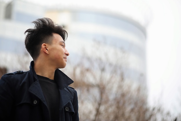 Photo jeune homme adulte asiatique dans la rue se présentant à la caméra