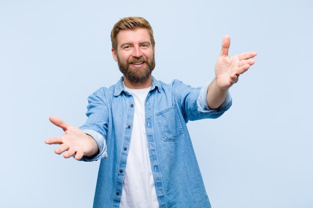 Jeune homme adulte blond souriant souriant donnant un câlin de bienvenue chaleureux, amical, aimant, se sentant heureux et adorable