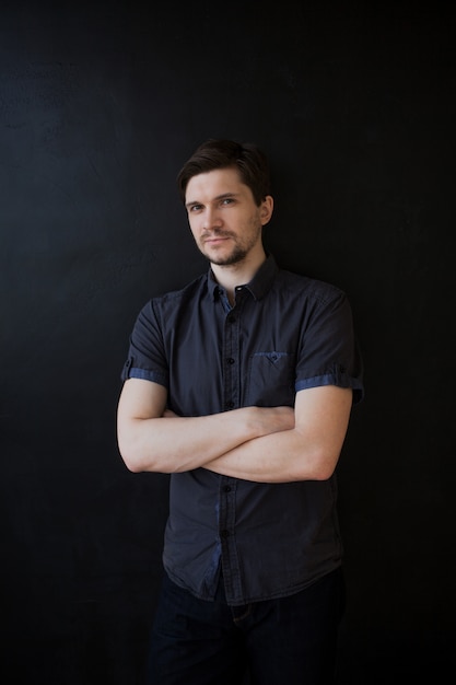 Jeune homme adulte dans une chemise grise. Portrait d'entreprise sur noir texturé