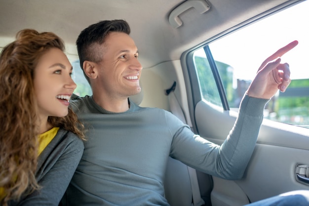 Jeune homme adulte et fille assise sur la banquette arrière en voiture