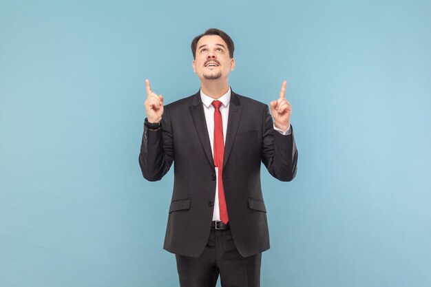 Jeune homme adulte avec moustache debout regardant vers le haut indiquant vers le haut à la maquette pour la publicité