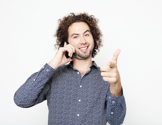 Jeune homme adulte parlant au téléphone debout sur fond blanc faisant signe ok avec les doigts