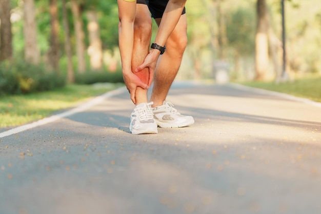 Jeune homme adulte avec ses douleurs musculaires pendant l'exécution d'un coureur ayant mal à la jambe en raison de blessures sportives et d'un concept médical