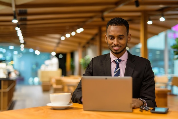 Jeune homme d'affaires africain dans un café utilisant un ordinateur portable