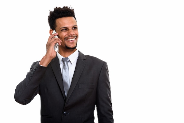 Jeune homme d'affaires africain heureux souriant tout en parlant au téléphone mobile et en pensant