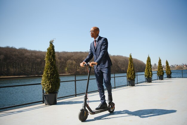 Jeune homme d'affaires africain monté sur un scooter électrique