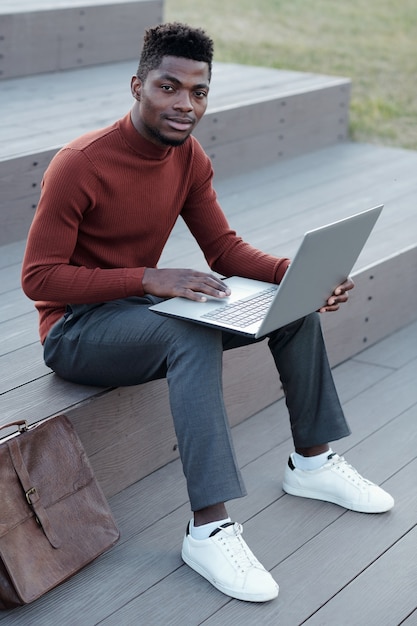 Jeune homme d'affaires africain réussi utilisant un ordinateur portable