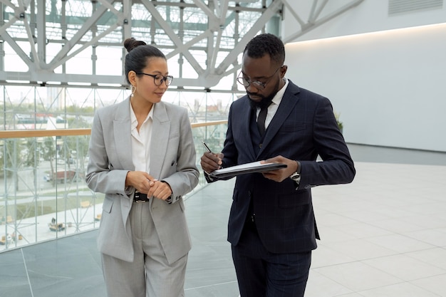 Jeune homme d'affaires africain signant un contrat après avoir négocié avec un partenaire