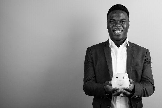 jeune homme d'affaires africain vêtu d'un costume contre le mur blanc. noir et blanc