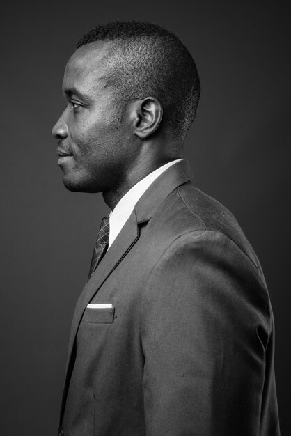 jeune homme d'affaires africain vêtu d'un costume contre le mur gris. noir et blanc