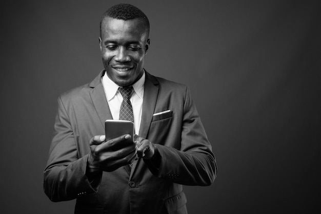 jeune homme d'affaires africain vêtu d'un costume contre le mur gris. noir et blanc