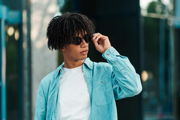 jeune homme d'affaires afro-américain aux cheveux bouclés levant les yeux et sortant d'un bâtiment portant