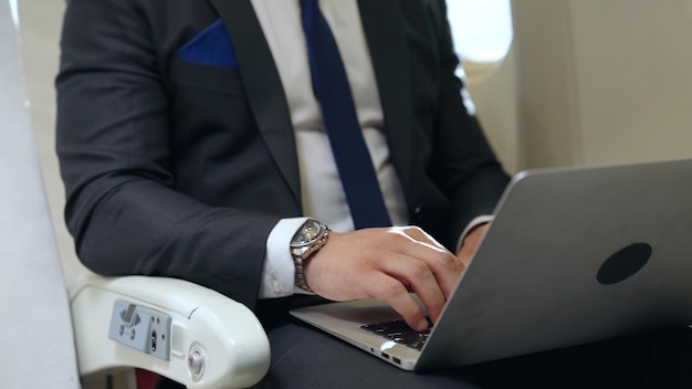 Jeune homme d'affaires à l'aide d'un ordinateur portable en avion. Concept de voyage d'affaires.
