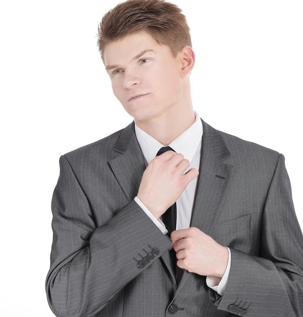 Jeune homme d'affaires ajustant sa cravate isolée sur fond blanc