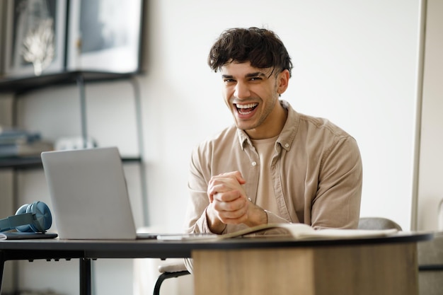 Jeune homme d'affaires arabe excité à l'ordinateur portable se frottant les mains sur le lieu de travail