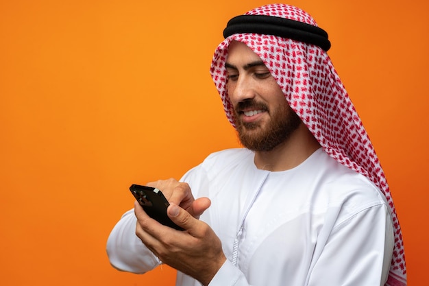 Jeune homme d'affaires arabe utilisant un smartphone sur fond orange