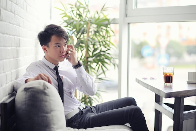 Un jeune homme d'affaires asiatique attend un partenaire dans un café. Réunion d'affaires au restaurant. Un jeune coréen parle au téléphone dans un café.