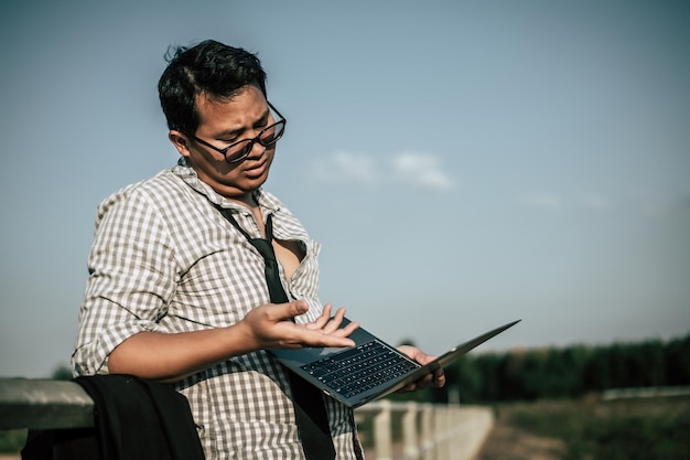 Jeune homme d'affaires asiatique avec un ordinateur portable portant une chemise et une cravate avec un short et des lunettes avec des problèmes et le stress ou la déception du travail à l'extérieur de l'espace de copie du bureau de l'entreprise