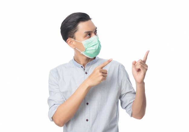 Jeune homme d'affaires asiatique portant un masque hygiénique et pointant vers le haut, prévenir l'infection, 2019-nCoV ou coronavirus.