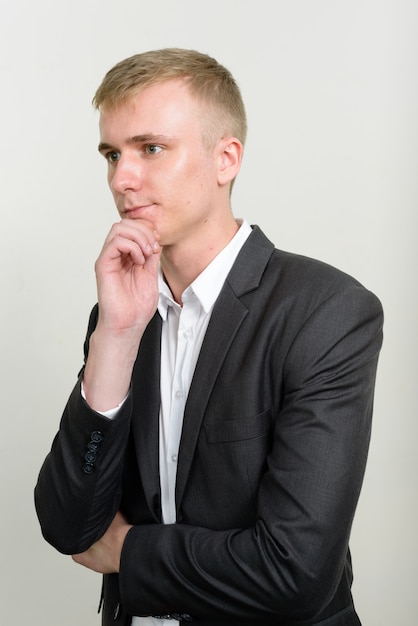 jeune homme d'affaires aux cheveux blonds portant costume sur blanc