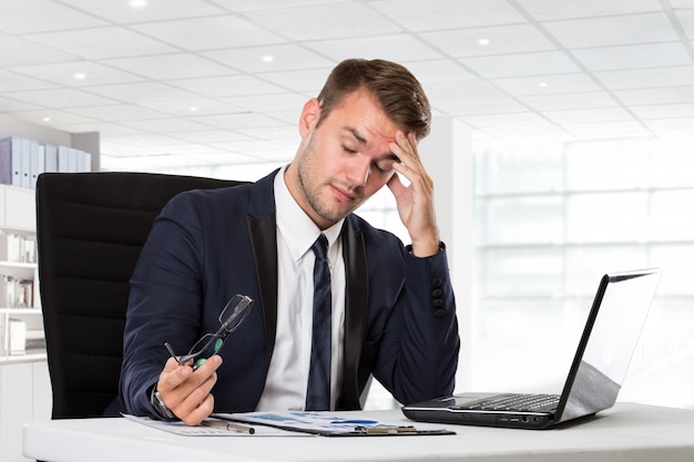 Jeune homme d'affaires ayant des maux de tête, stressé par son travail