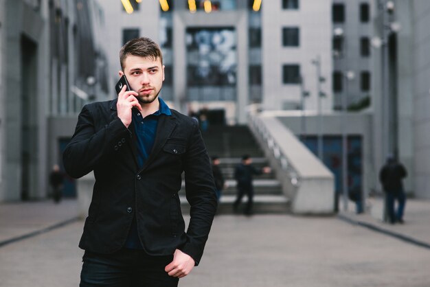 Jeune homme d'affaires avec une barbe près d'un immeuble moderne