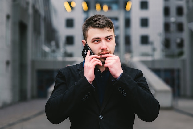 Jeune homme d'affaires avec une barbe près d'un immeuble moderne