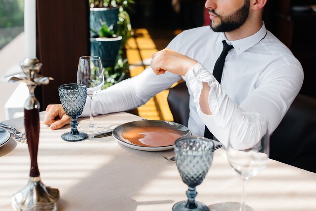 Un jeune homme d'affaires barbu est assis à une table dans un bon restaurant et attend sa commande. Service à la clientèle dans la restauration.