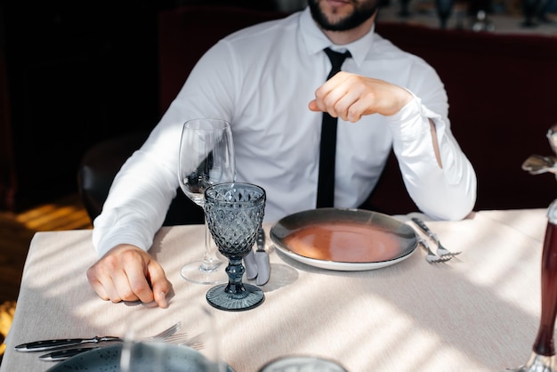 Un jeune homme d'affaires barbu est assis à une table dans un restaurant raffiné et attend sa commande Service client dans la restauration