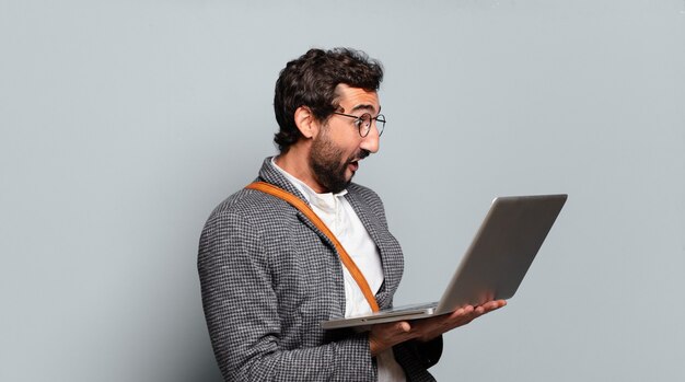 Jeune homme d'affaires barbu et fou avec un ordinateur portable