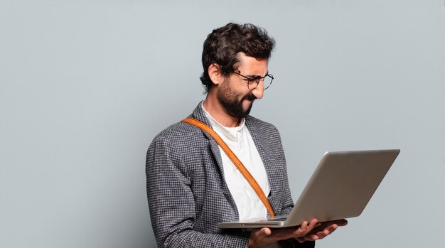 Jeune homme d'affaires barbu et fou avec un ordinateur portable