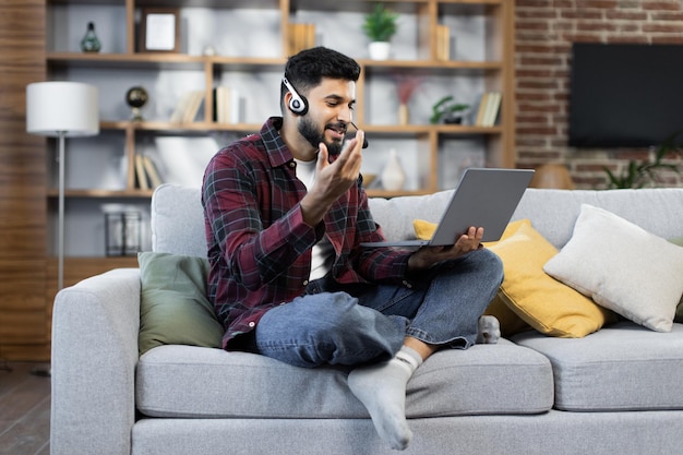 Jeune homme d'affaires barbu travaillant sur ordinateur parlant en ligne à l'aide d'un casque