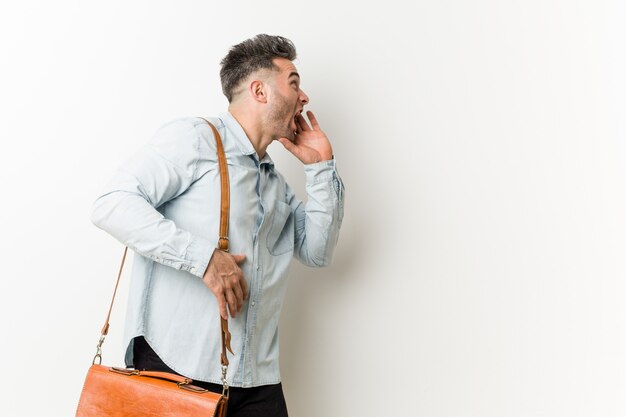 Jeune homme d'affaires beau criant et tenant la paume près de la bouche ouverte.