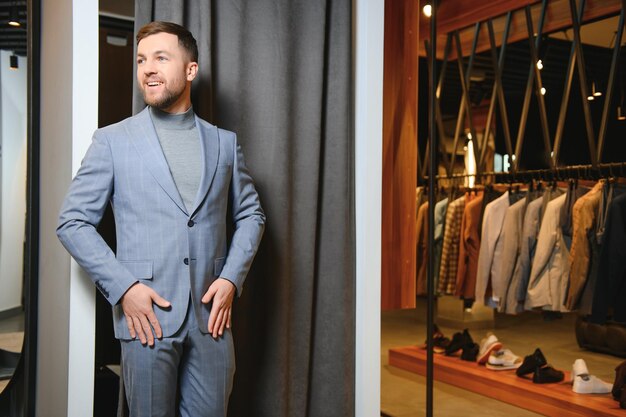 Photo un jeune homme d'affaires beau et moderne cherchant et choisissant un costume classique dans le magasin de costumes