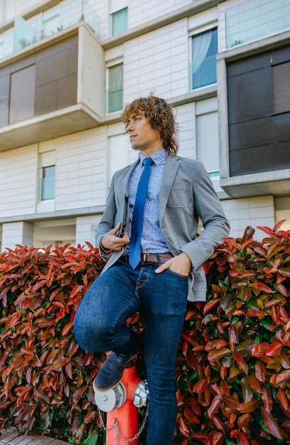 Jeune homme d'affaires avec blazer et jeans s'appuyant sur une bouche d'incendie