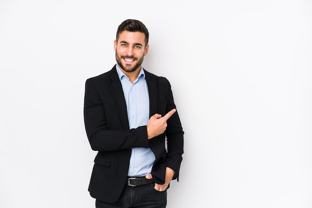 Jeune homme d'affaires caucasien sur blanc isolé souriant et pointant de côté, montrant quelque chose à l'espace vide.