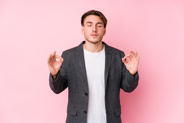 Jeune homme d'affaires caucasien posant isolé se détend après une dure journée de travail, elle effectue du yoga.