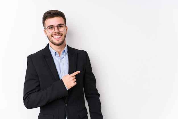 Jeune homme d'affaires caucasien souriant et pointant de côté, montrant quelque chose à l'espace vide.