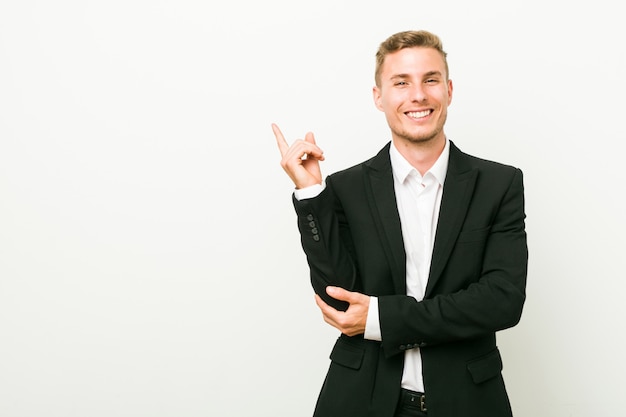 Jeune homme d'affaires caucasien souriant pointant gaiement avec l'index.